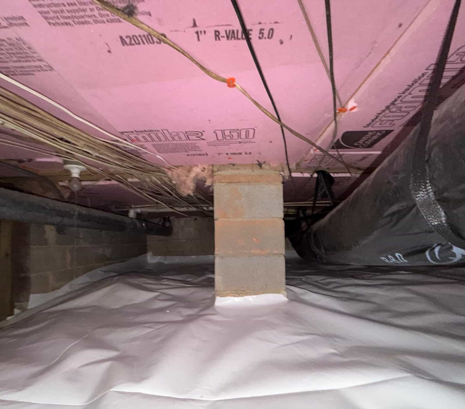 Block pier wrapped at its base by white crawl space liner under pink foam insulation and ductwork.