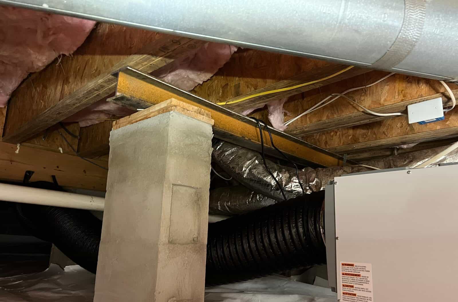 Crawl space dehumidifier installed beside a block pier, with the liner on the floor.