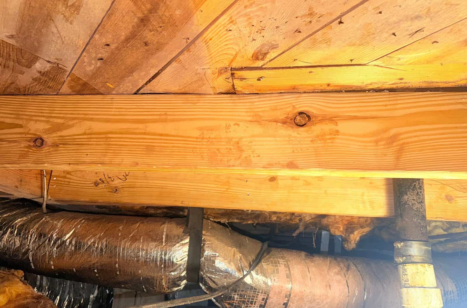 New sistered lumber fastened under a subfloor above foil ductwork and a drain pipe.