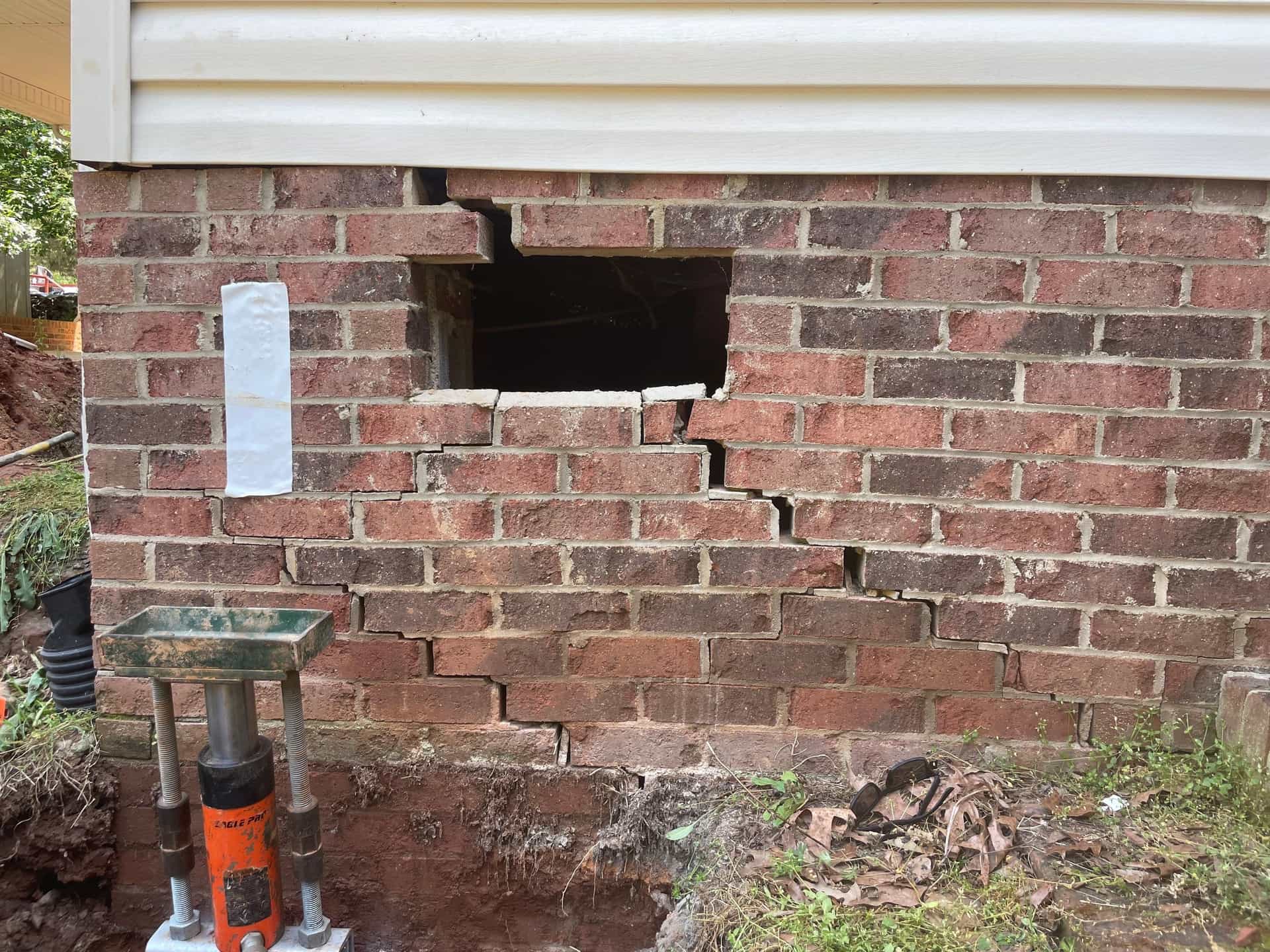 HydroHelp911 Crawl Space & Foundation Repair installing steel piers with a hydraulic ram to repair stair step cracks.