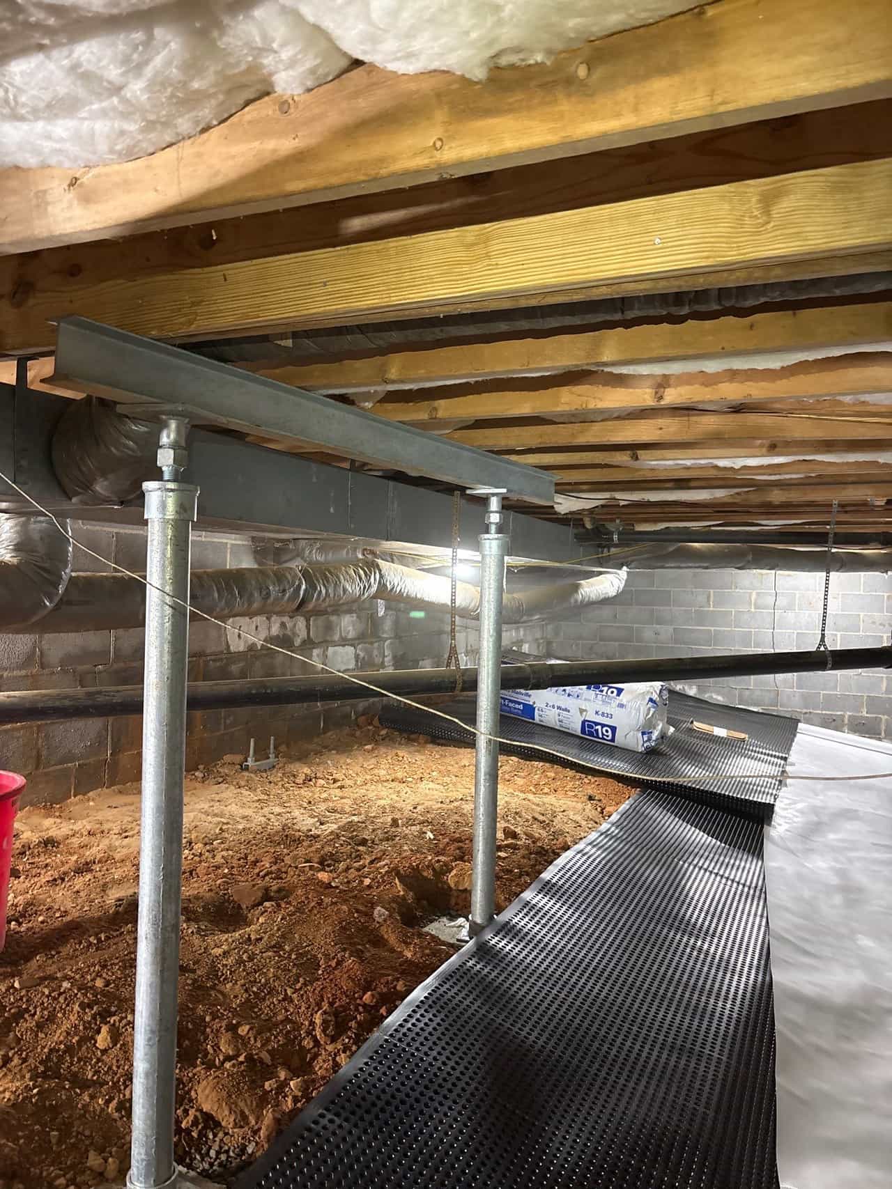 HydroHelp911 Crawl Space & Foundation Repair installing crawl space jacks and drainage matting for stabilization.