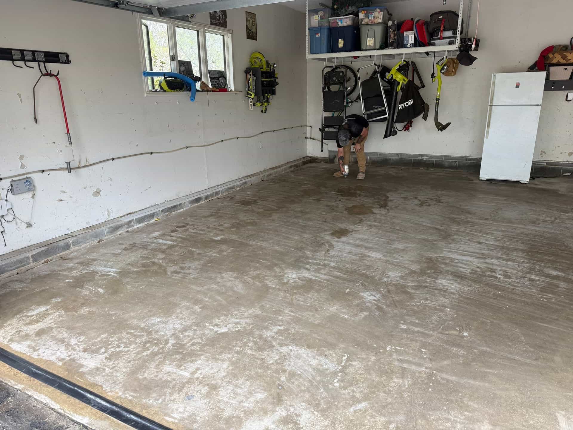 HydroHelp911 Crawl Space & Foundation Repair technician inspecting a cracked concrete garage floor with efflorescence.