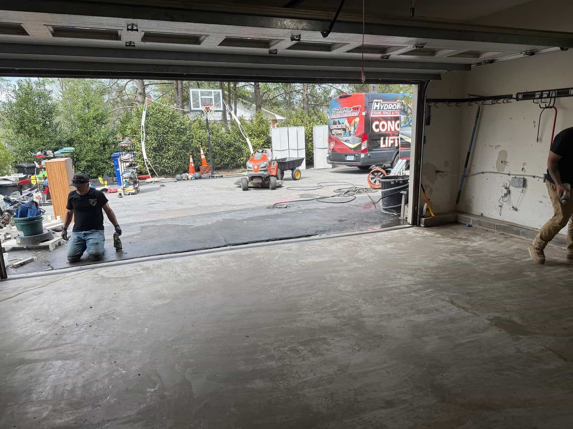 HydroHelp911 Crawl Space & Foundation Repair crew working on garage floor leveling with branded truck