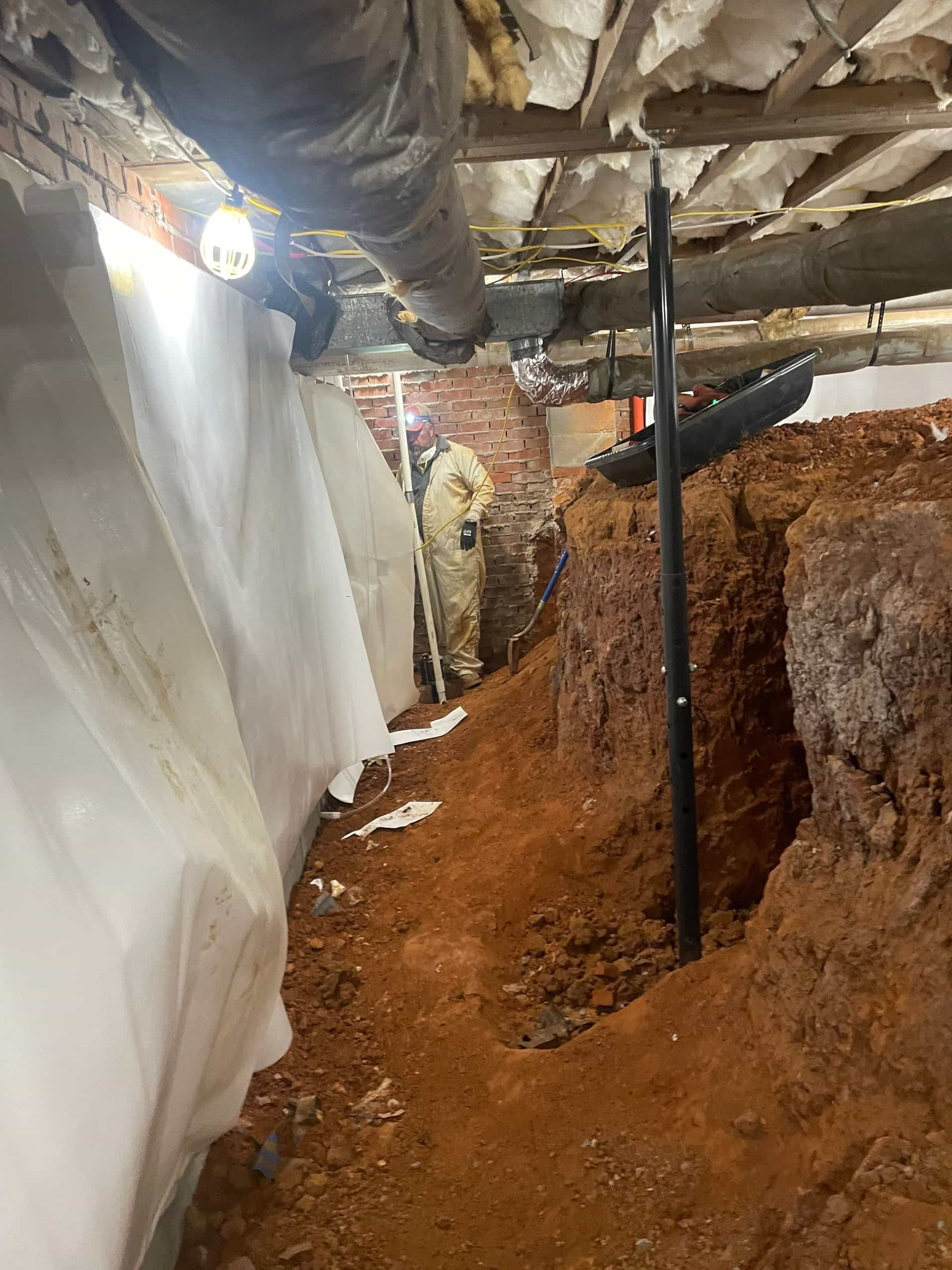 HydroHelp911 Crawl Space & Foundation Repair crew installing a drainage trench and vapor barrier in a crawl space