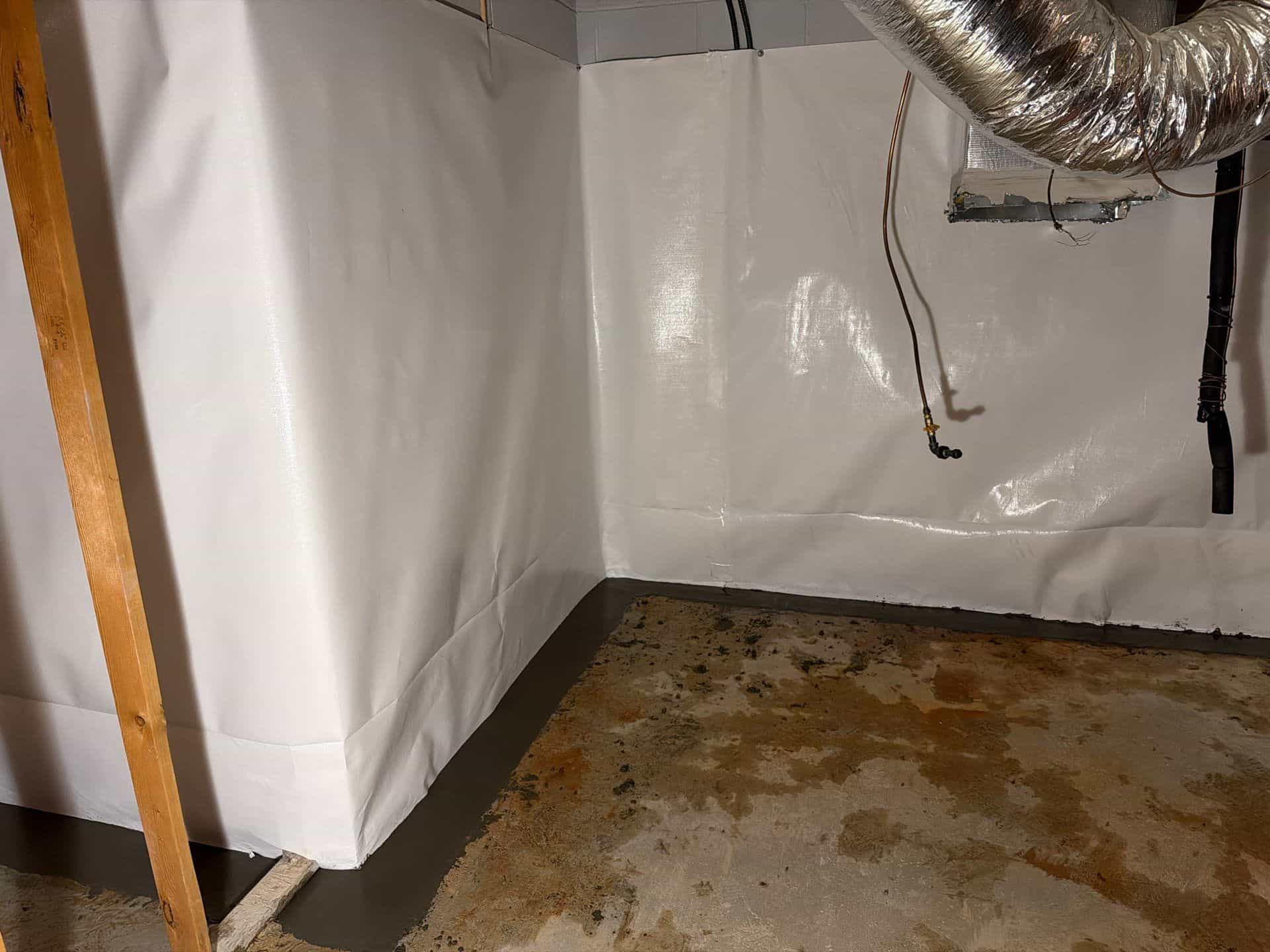 HydroHelp911 Crawl Space & Foundation Repair installing a white vapor barrier and interior drainage system in a basement.