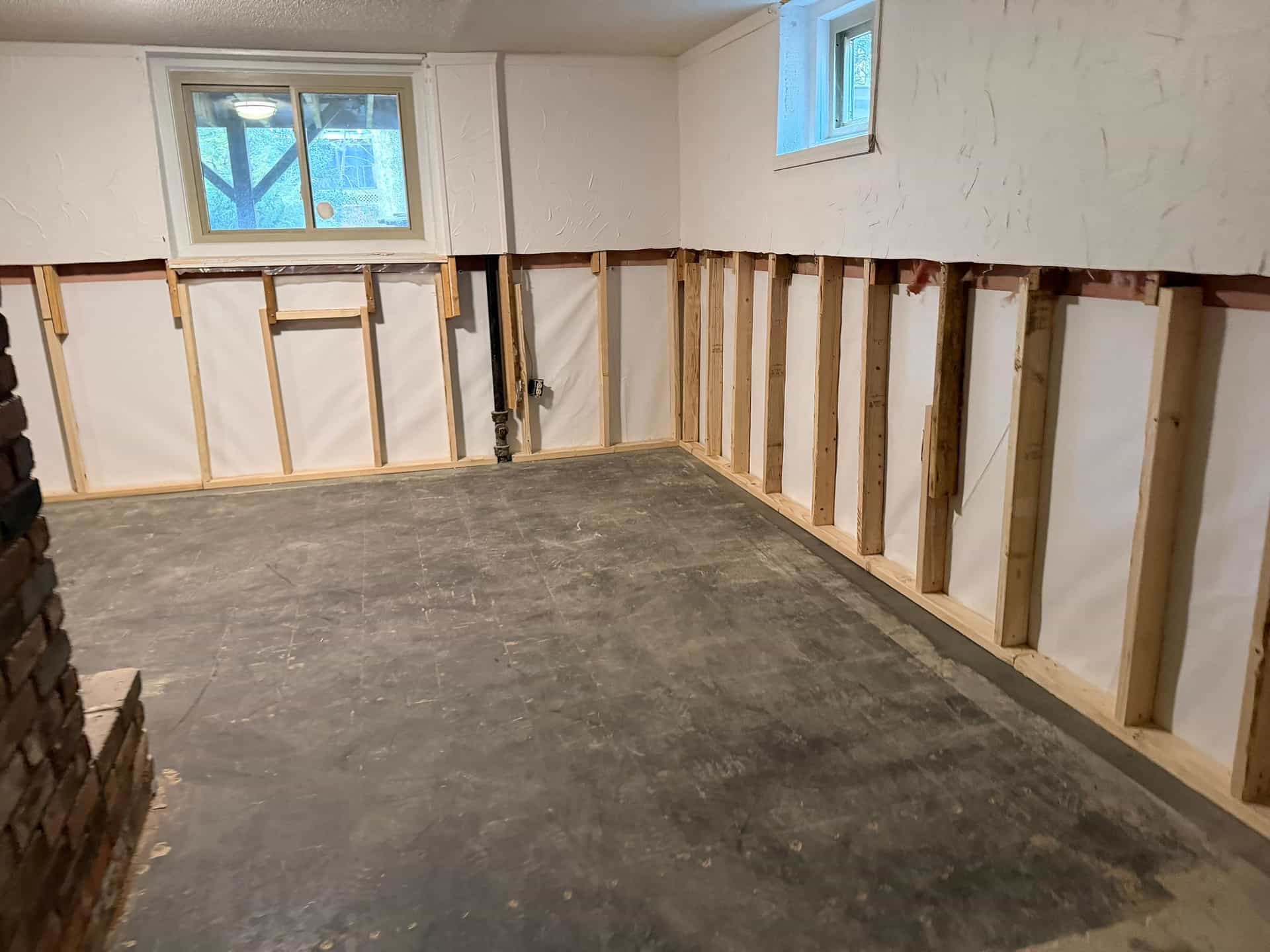 HydroHelp911 Crawl Space & Foundation Repair installing a basement wall liner and vapor barrier in a basement.