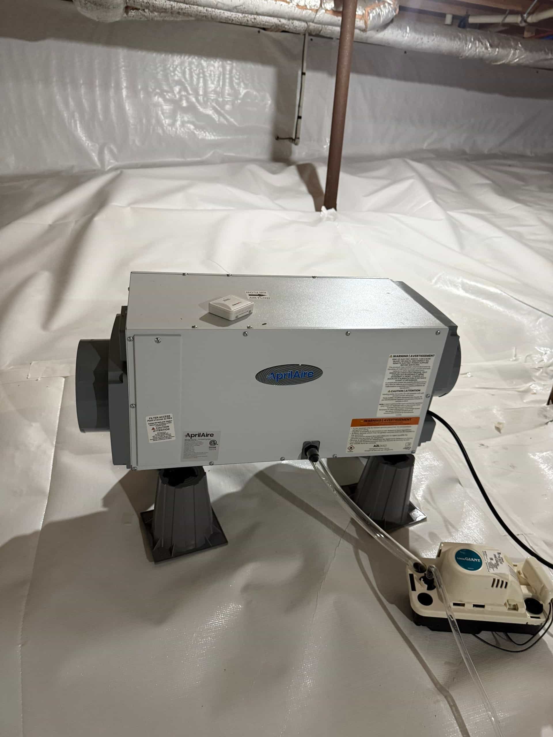 HydroHelp911 Crawl Space & Foundation Repair installing a crawl space dehumidifier on a white vapor barrier.