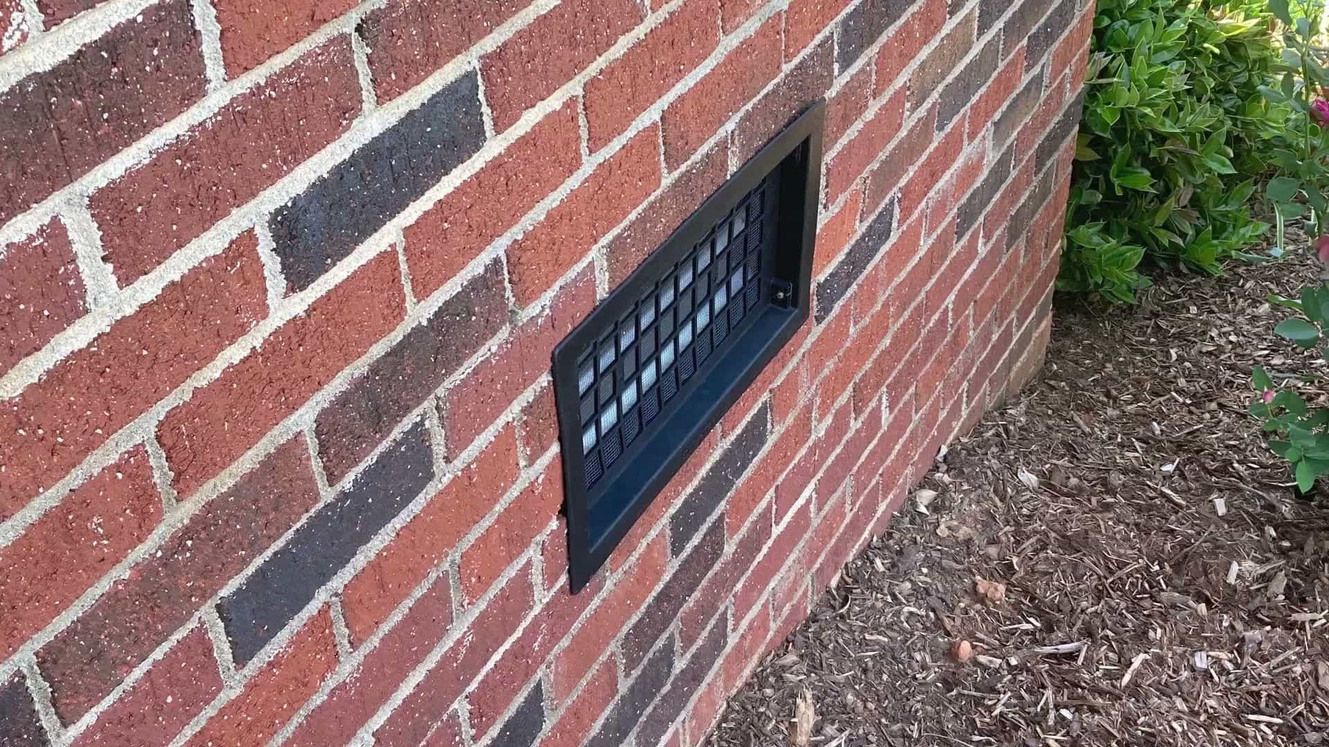 HydroHelp911 Crawl Space & Foundation Repair installing a crawl space vent cover in a brick foundation wall.