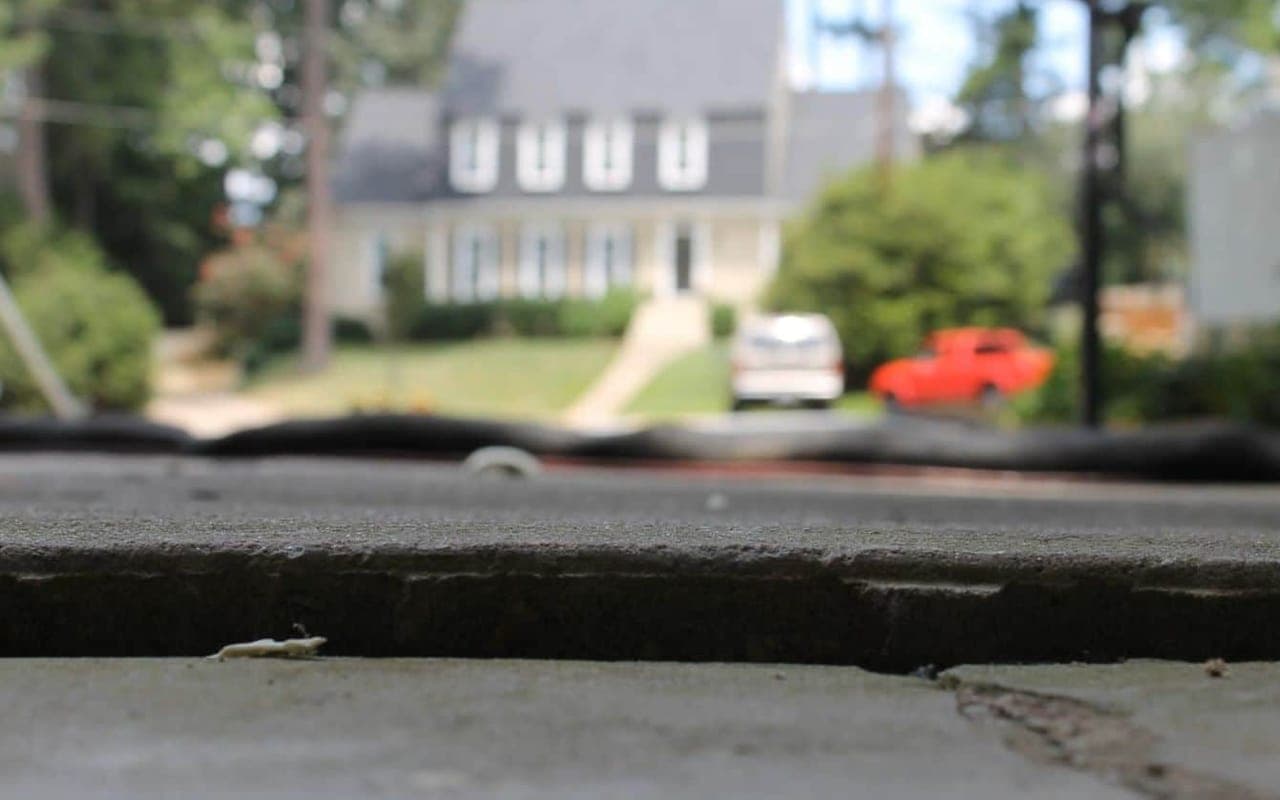 A low view along a sidewalk where one concrete section sits lower than the next