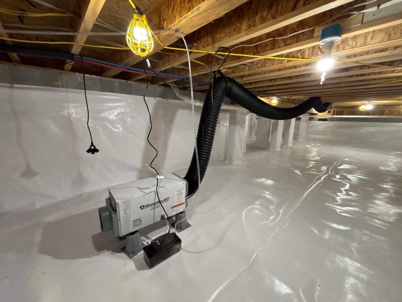 A crawl space dehumidifier set on a new white liner, with its duct run to the floor framing