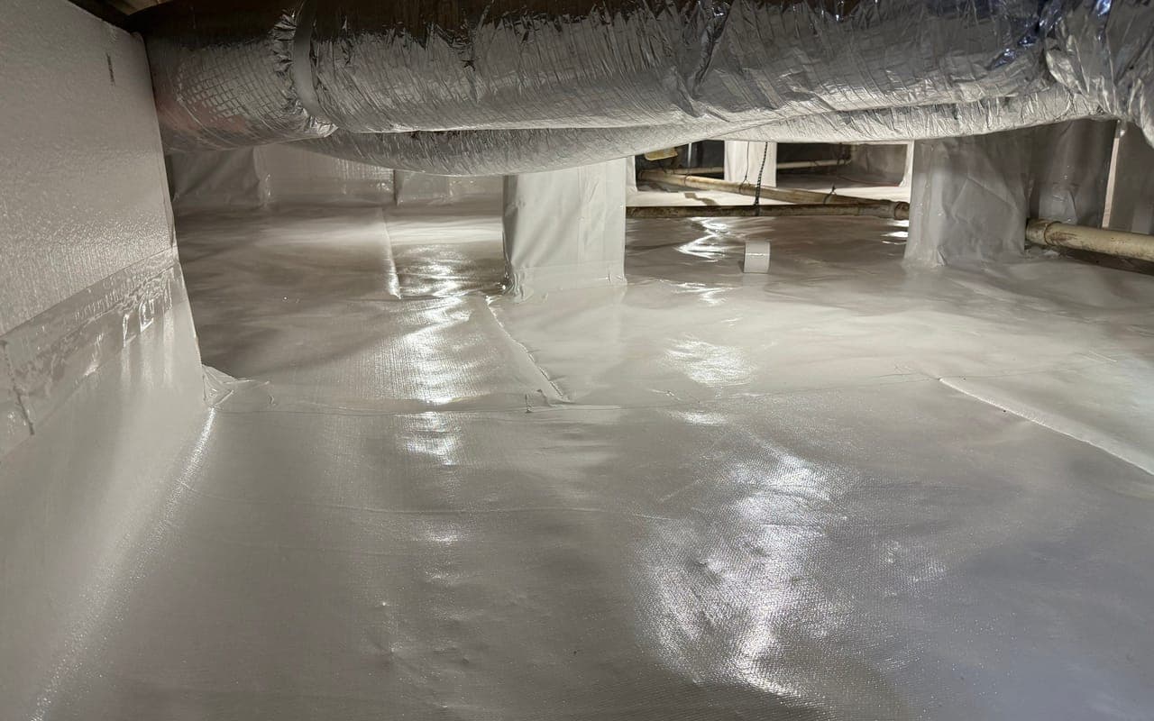 A finished crawl space encapsulation with a white liner over the ground, the foundation walls and the piers