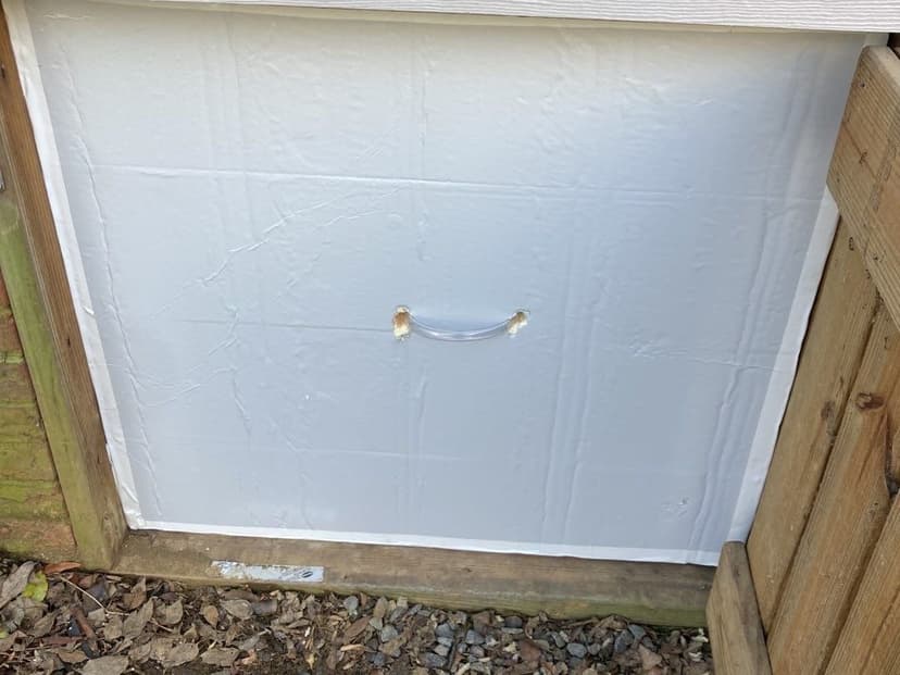 An insulated crawl space access door fitted into a foundation opening