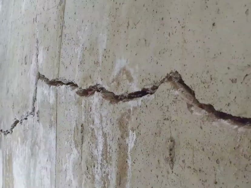 A wide crack across a poured concrete basement wall