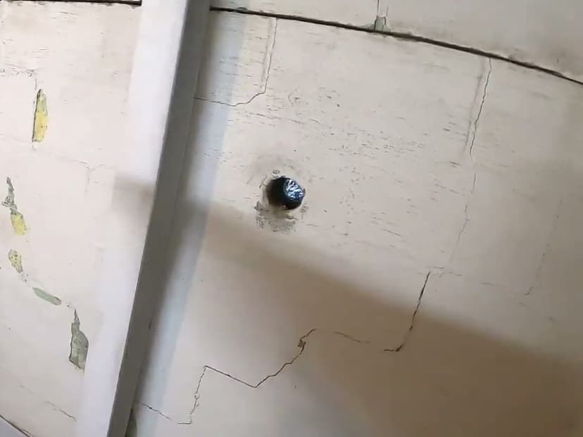 Horizontal and stair step cracks across a painted block basement wall