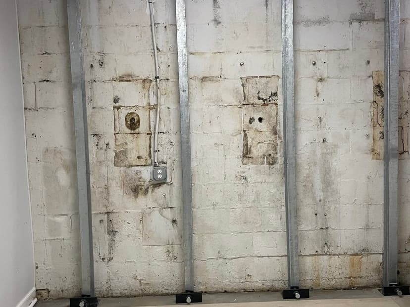 Steel beams fastened upright against a block basement wall