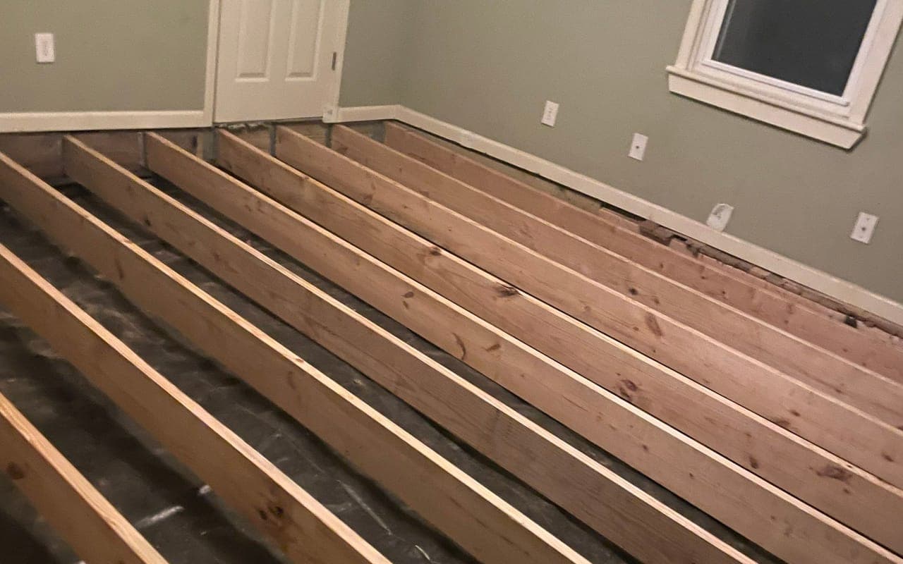 New wood floor joists in a room with the floor opened up during a framing repair