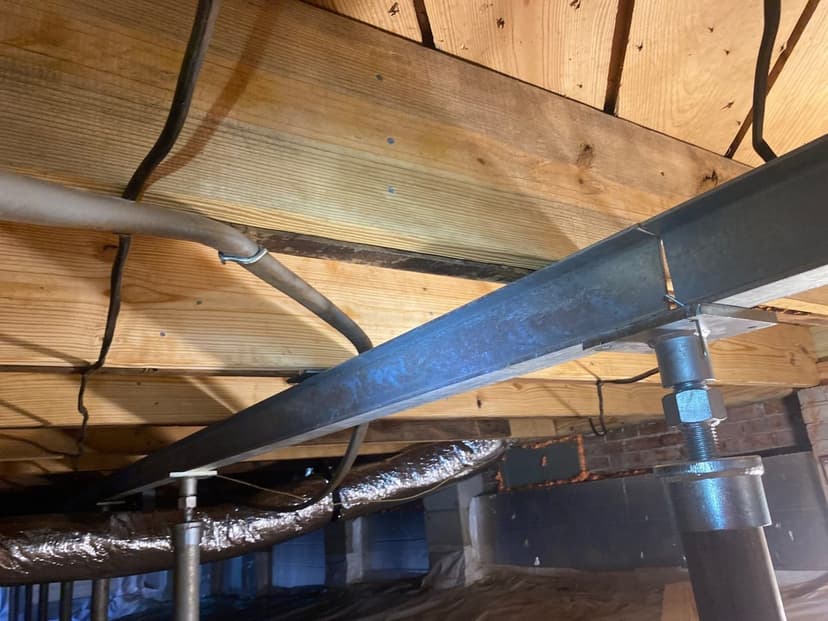 A steel beam on steel crawl space jacks under the floor joists