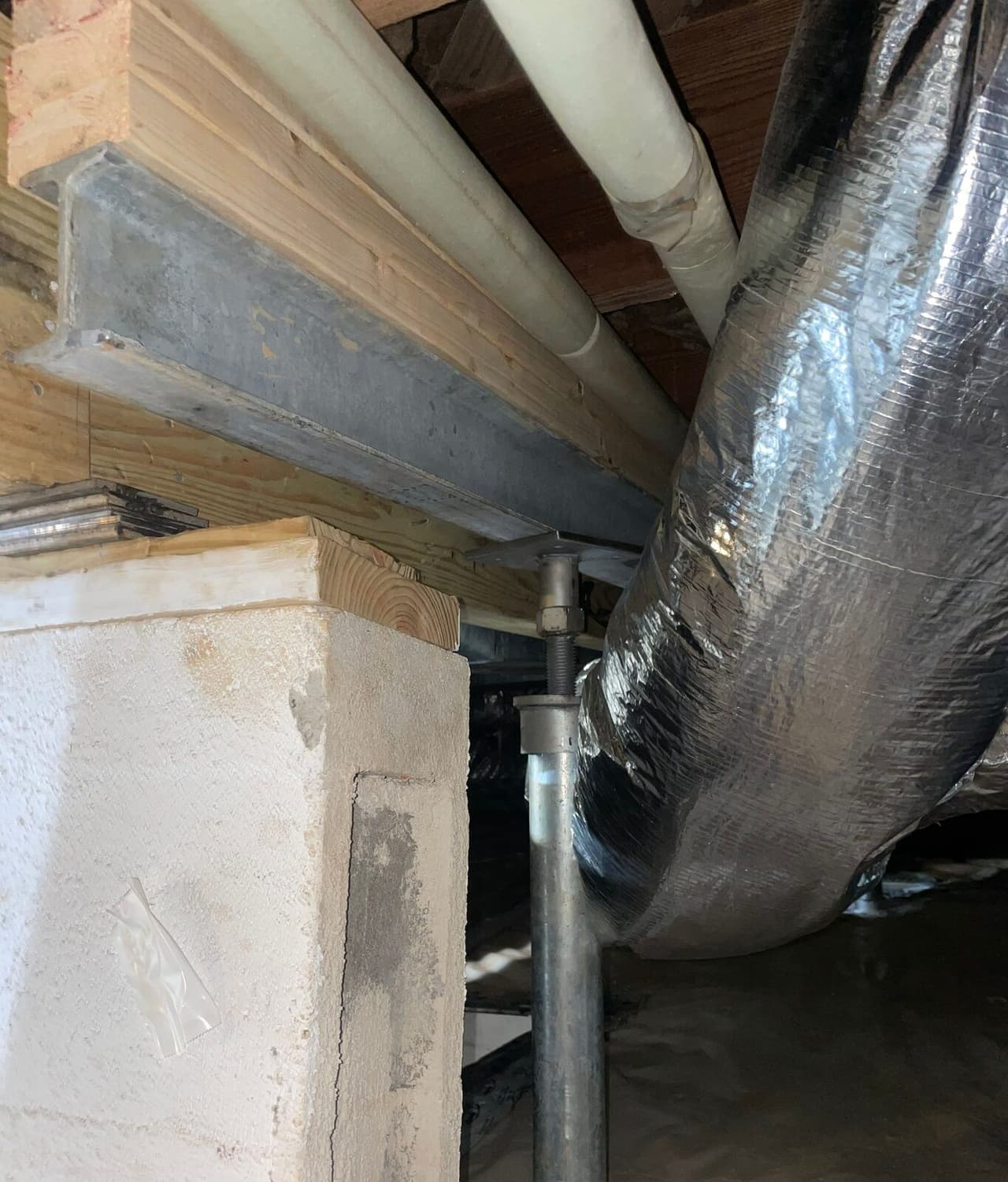 Steel support post bolted under a steel beam beside a masonry pier and a foil duct in a crawl space.