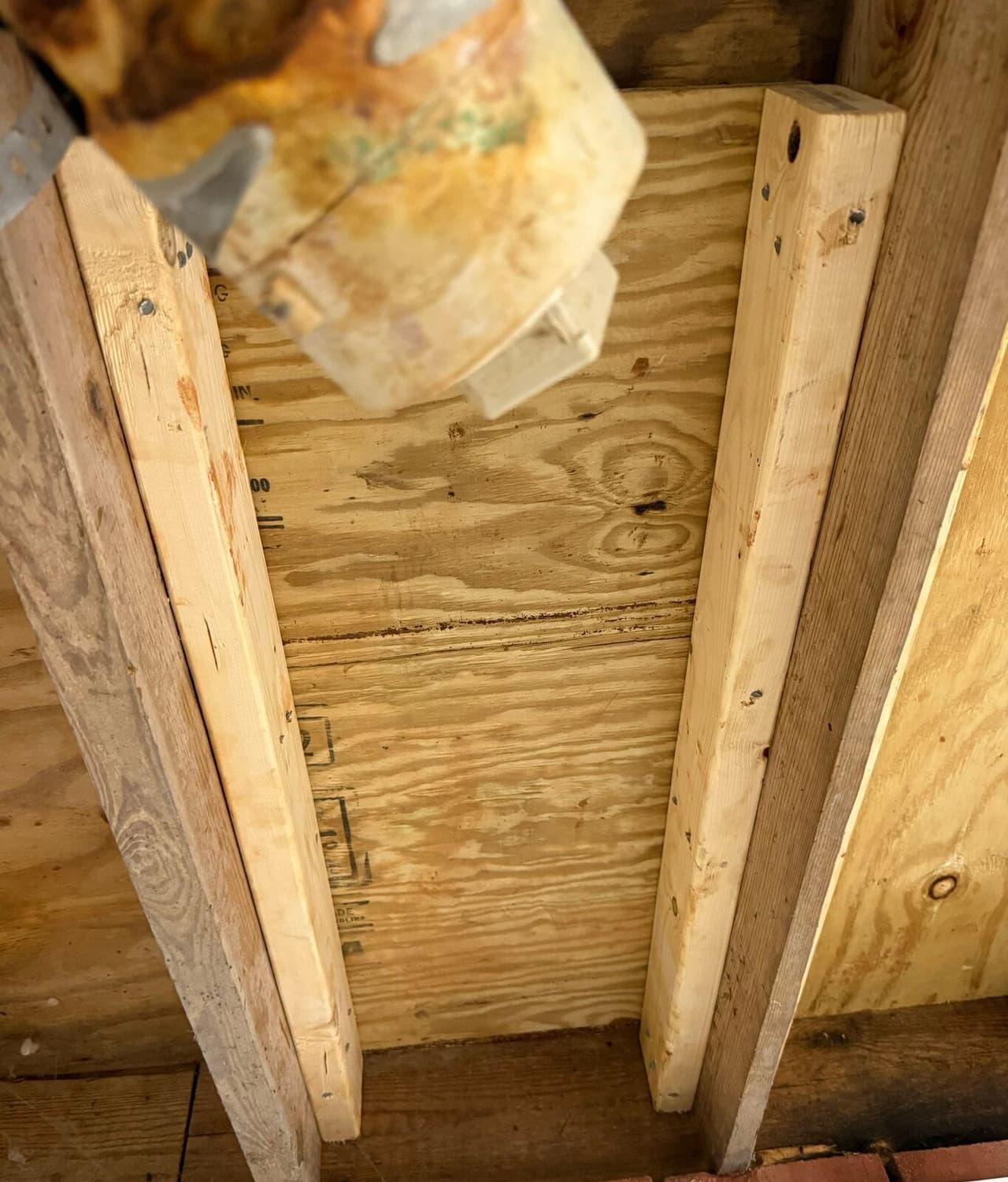 New lumber boards fastened alongside old joists beneath a plywood subfloor in a crawl space.