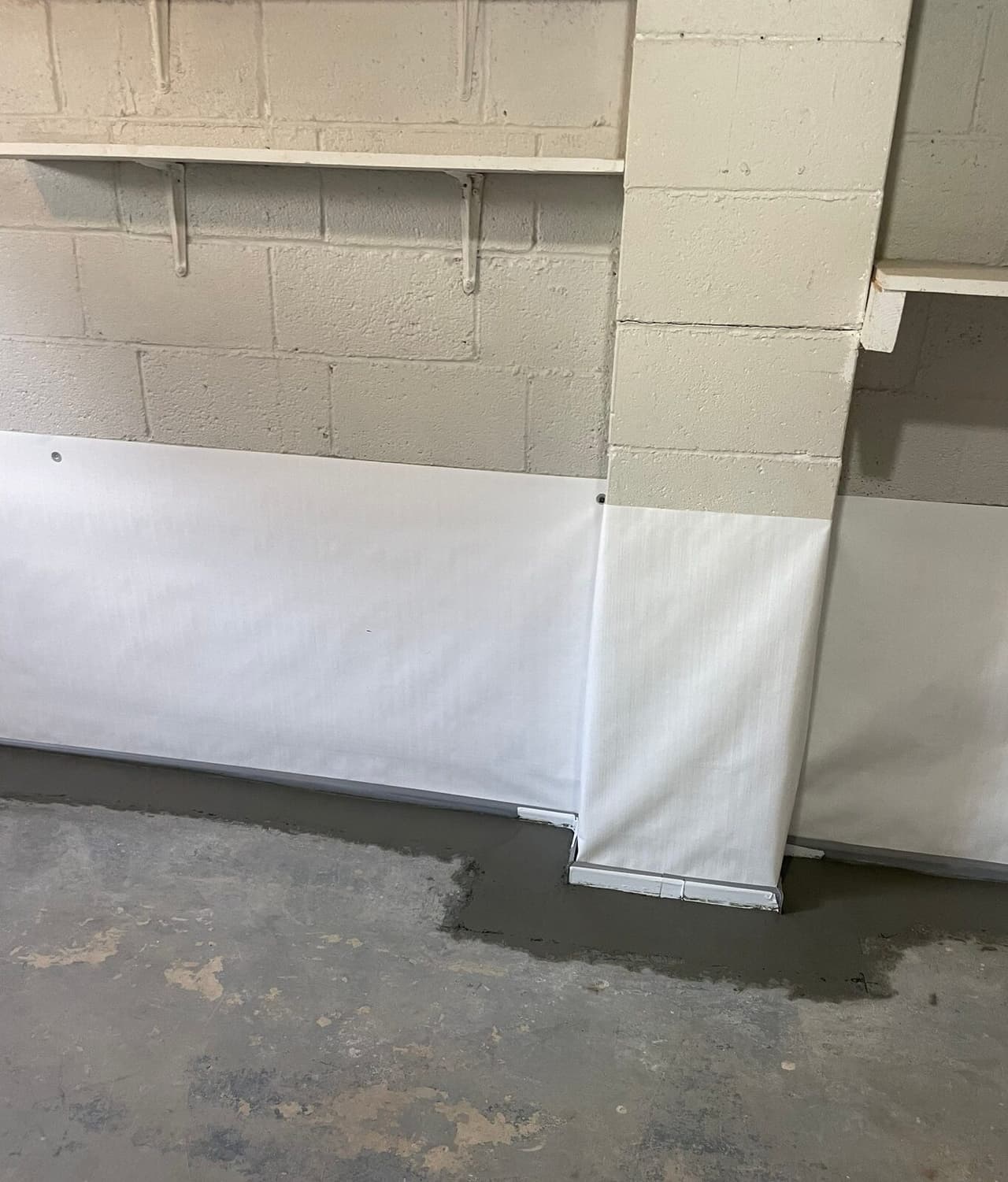 White wall liner wrapped around a block pilaster with fresh concrete along the floor edge.