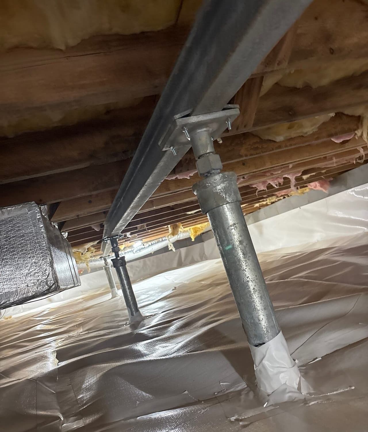 Steel beam supported by adjustable steel posts resting on a white crawl space liner.