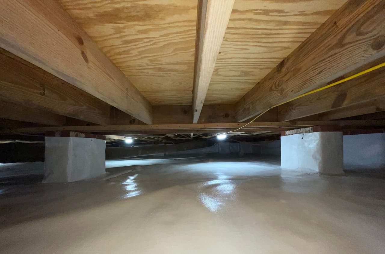 Crawl space with liner on the floor and two wrapped support piers under the beams.