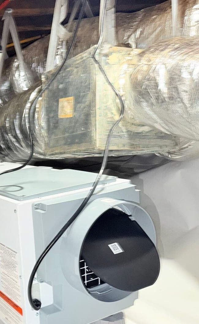 Crawl space dehumidifier on stands above white liner with ducts and water tanks behind it.