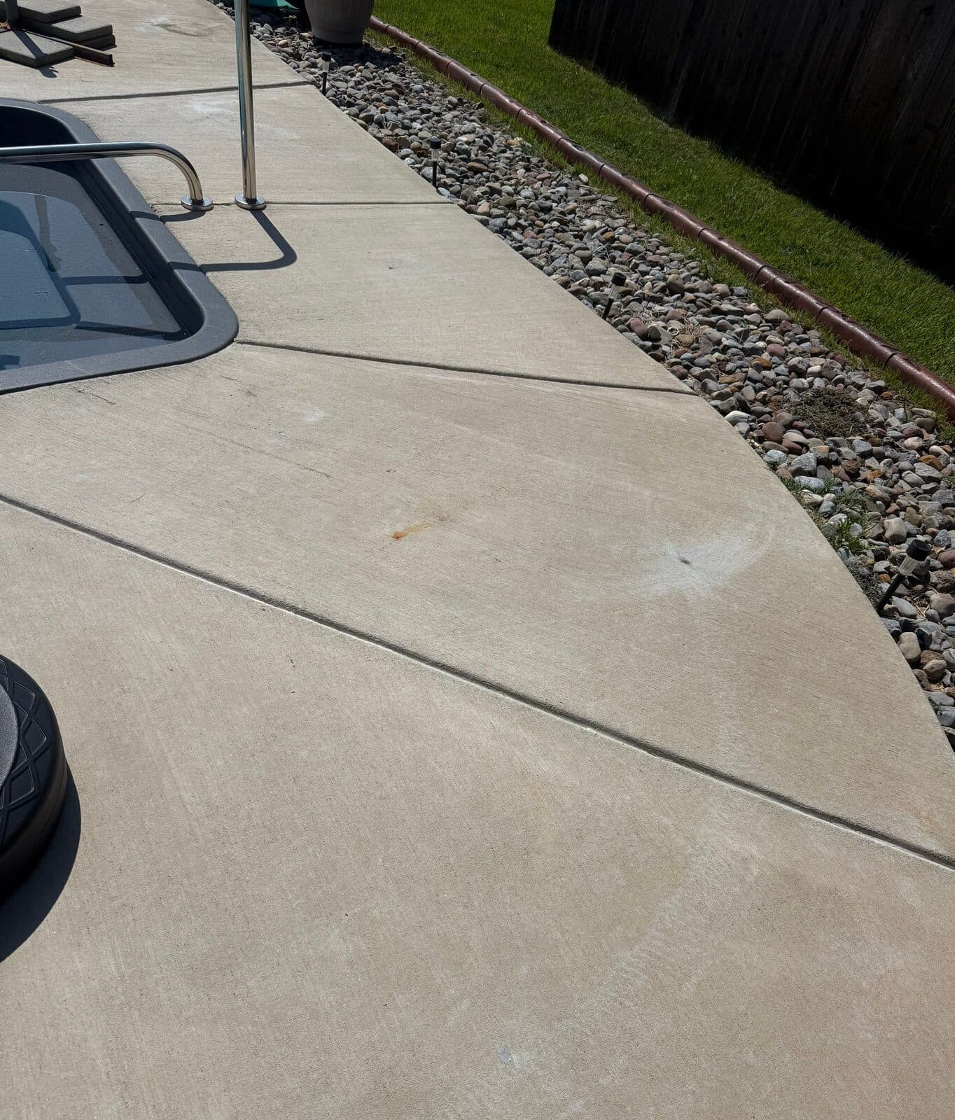 Pool deck slabs beside pool steps with level joints and a patched injection hole on the concrete.