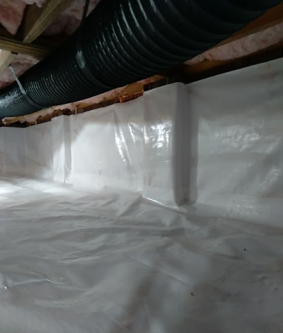 Crawl space liner sealed up the foundation walls and over the floor, with the seams taped.