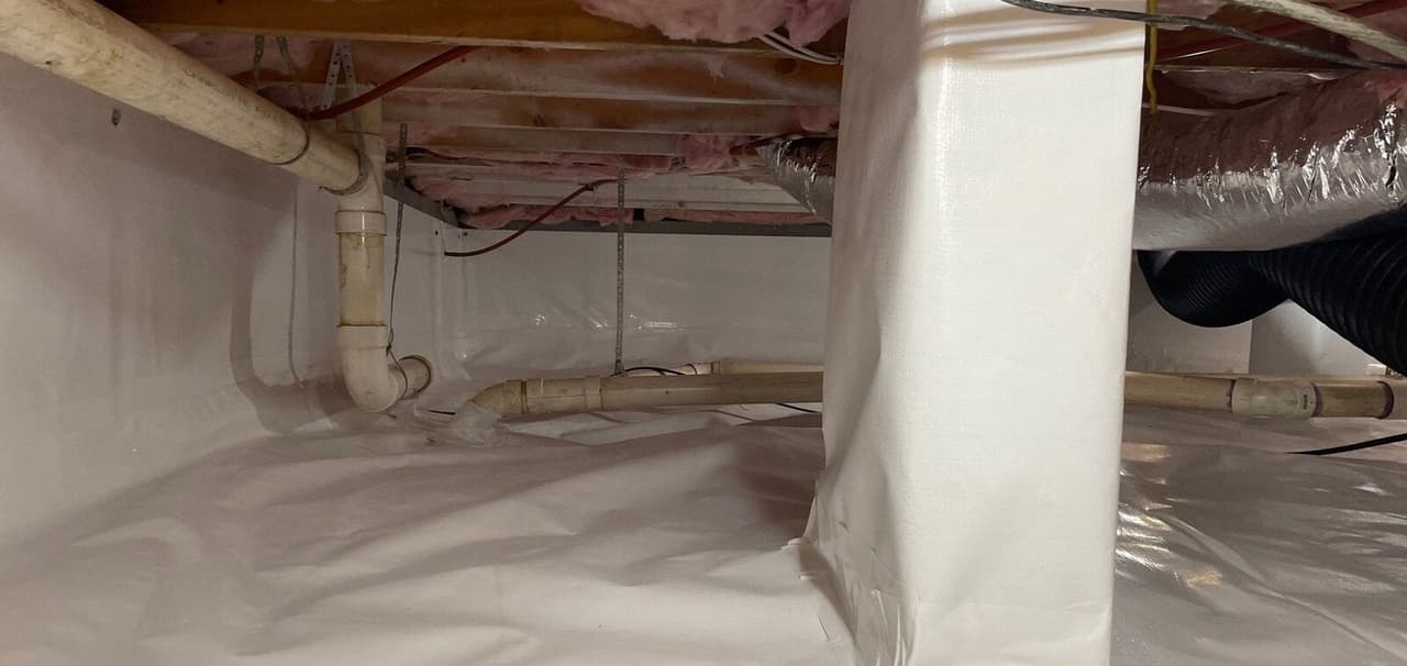 White crawl space liner sealed up the walls and around a wrapped pier.