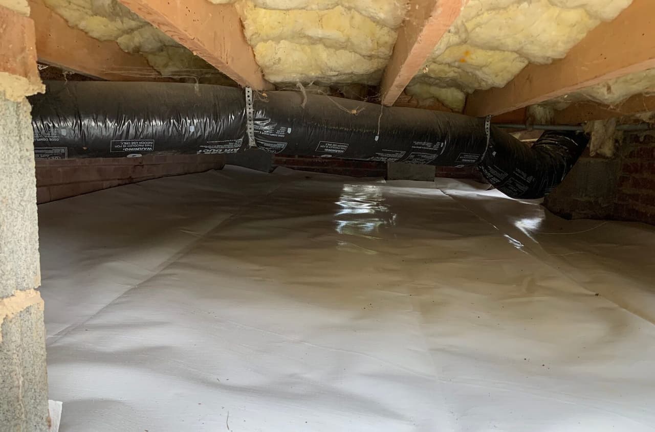 Finished crawl space with a white liner covering the floor under the ductwork.
