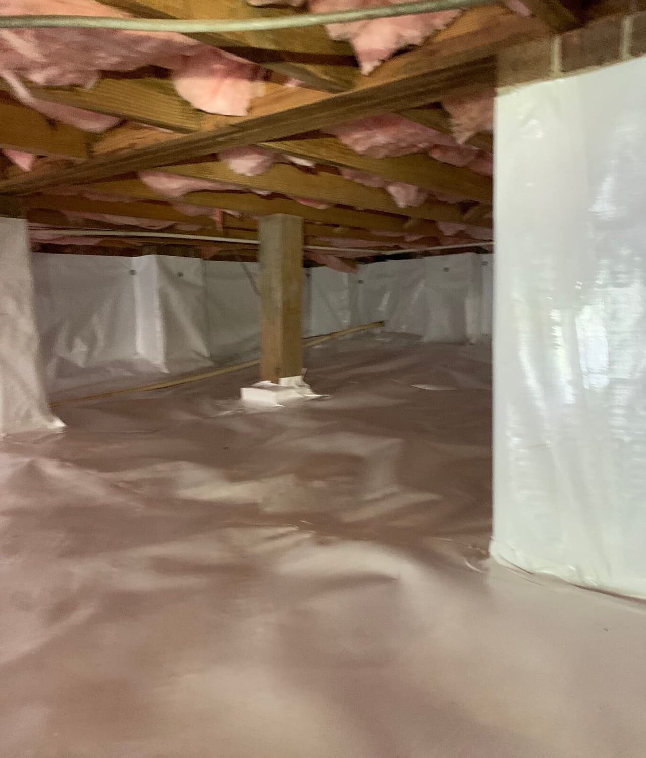 Crawl space liner sealed up the walls and around a wooden post.