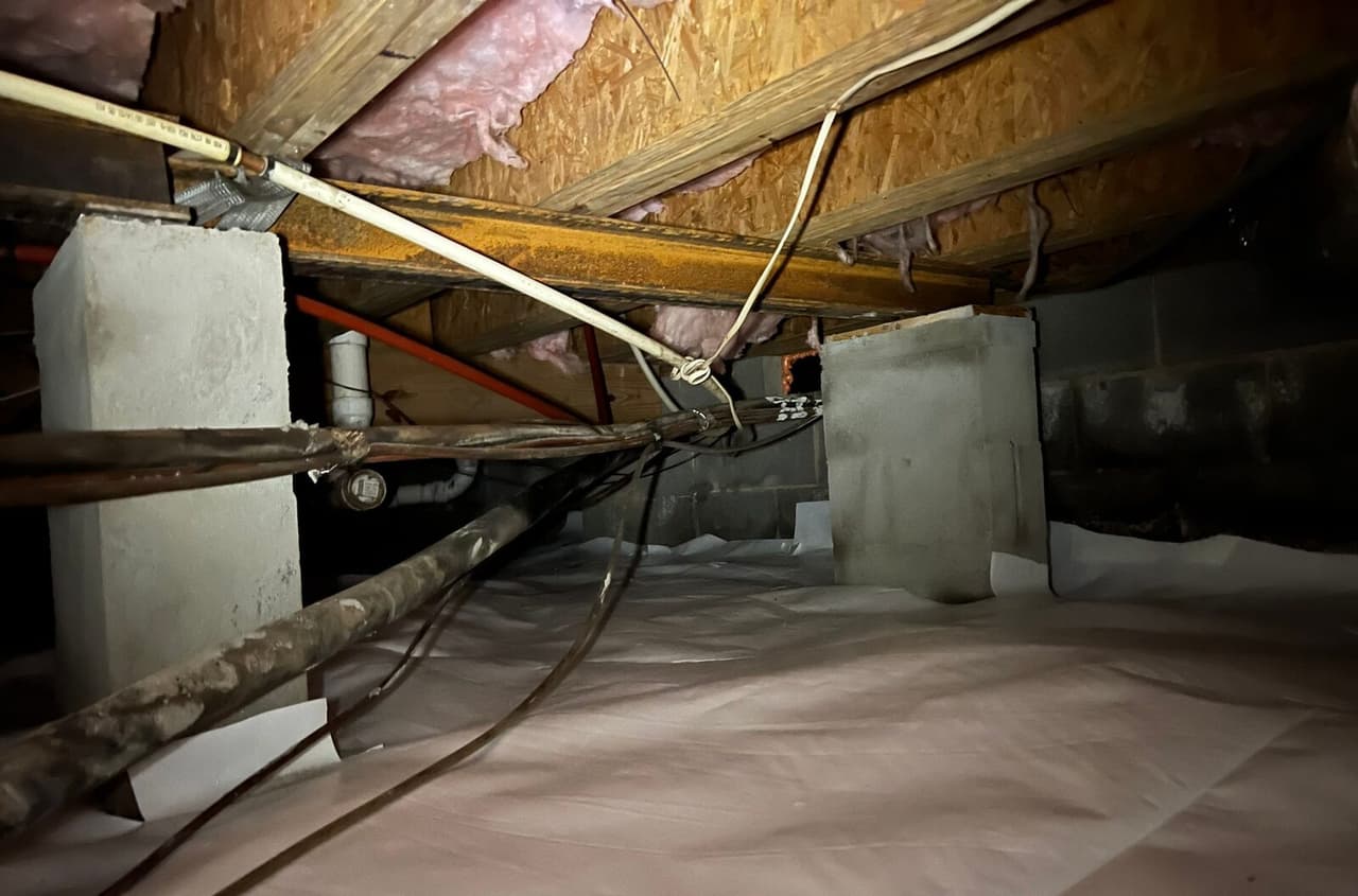 Crawl space liner over the floor around two block piers.