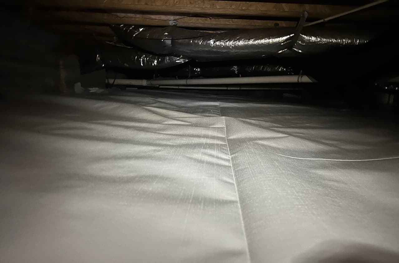 Crawl space liner laid over the floor with an overlapped seam.
