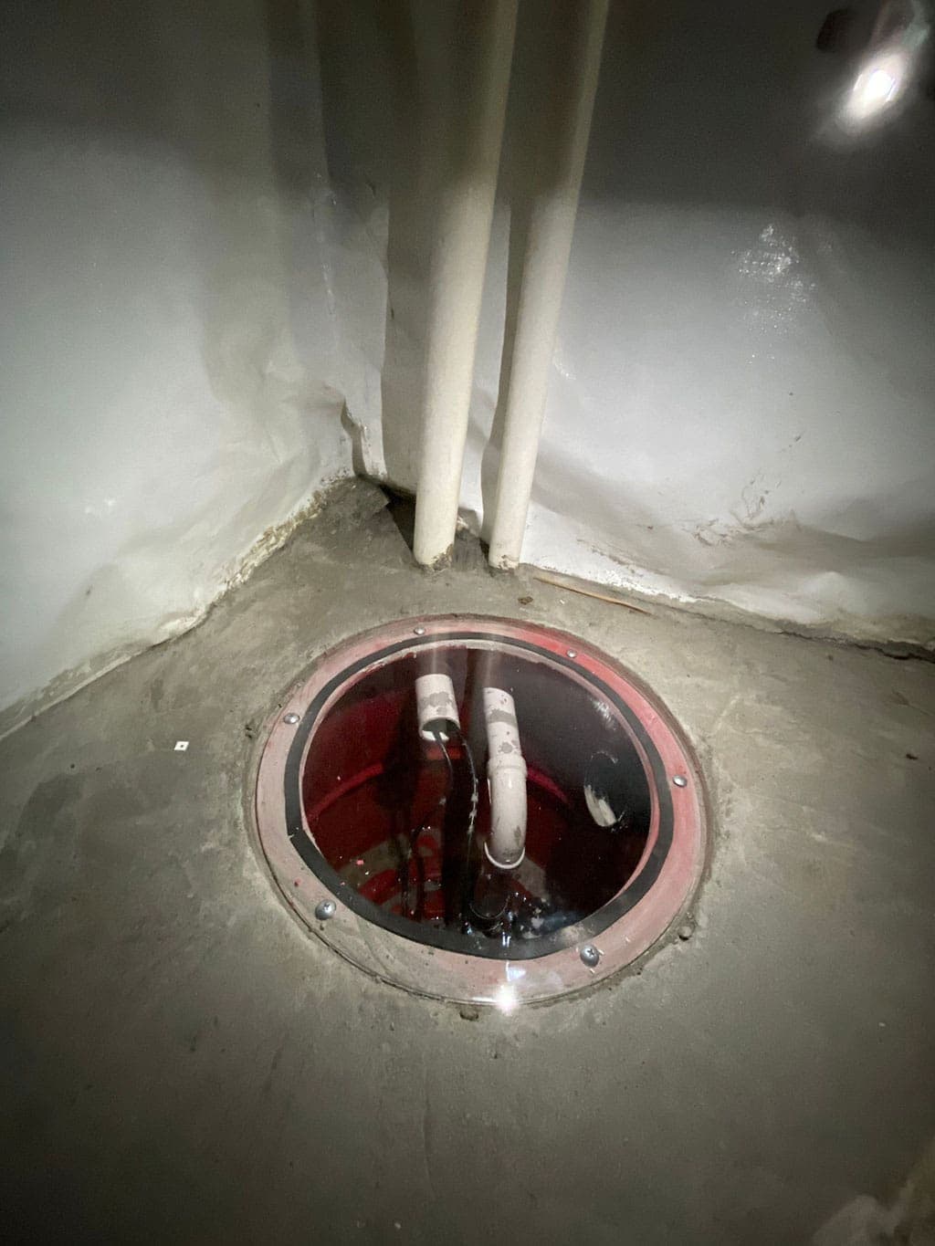 HydroHelp911 Crawl Space & Foundation Repair installing a sump pump with a sealed sump basin lid and discharge pipes.