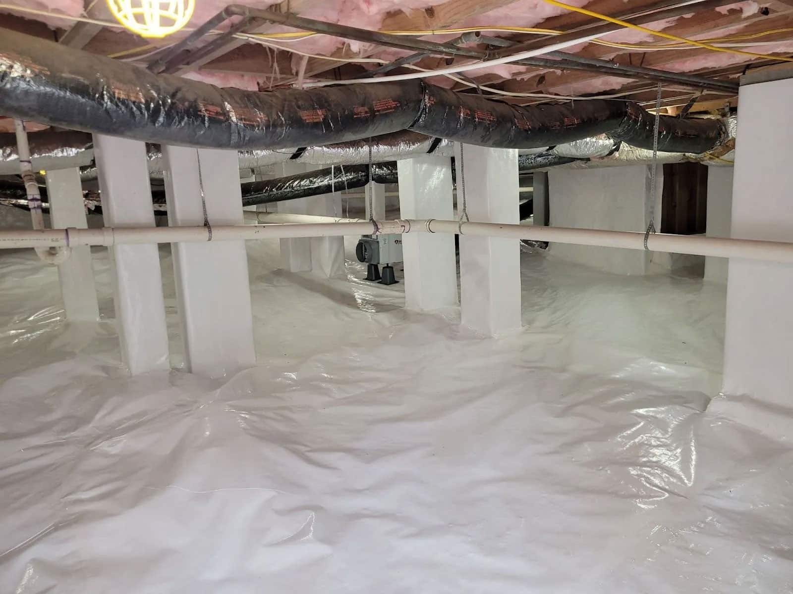 HydroHelp911 Crawl Space & Foundation Repair installing a white vapor barrier, dehumidifier, and insulation in a crawl space.