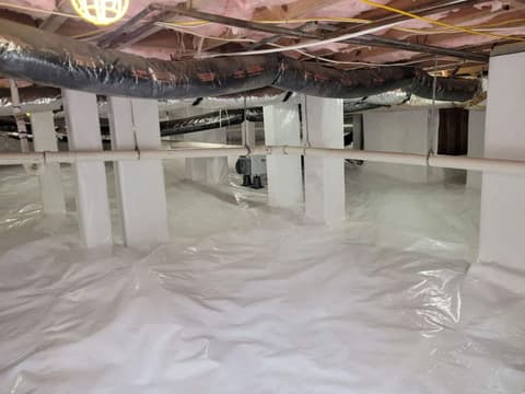 HydroHelp911 Crawl Space & Foundation Repair installing a white vapor barrier, dehumidifier, and insulation in a crawl space.
