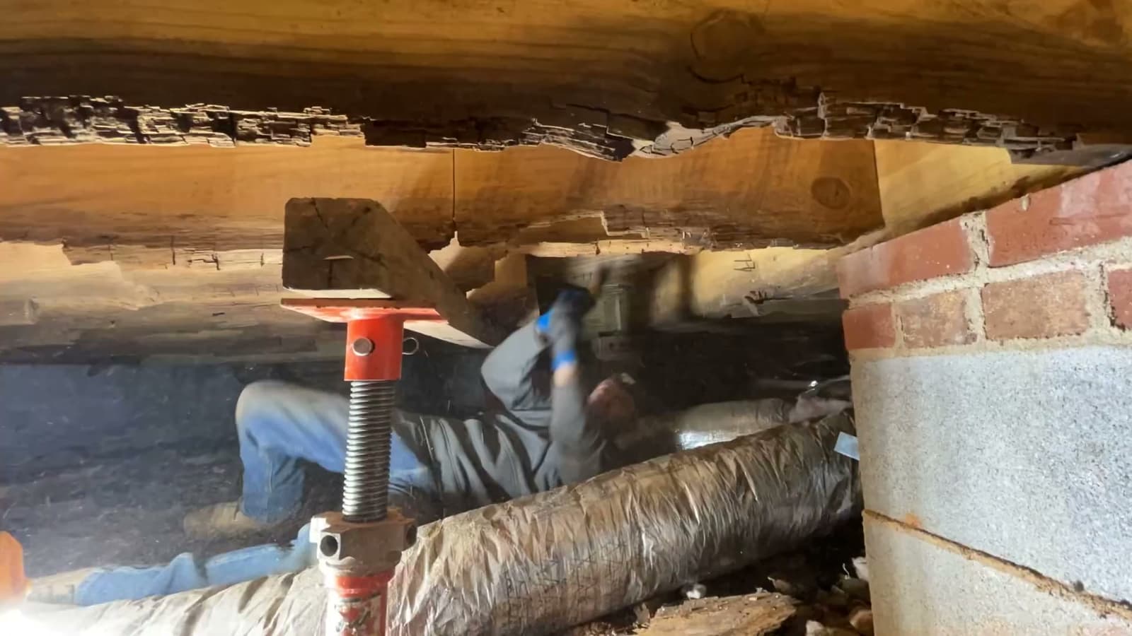 HydroHelp911 Crawl Space & Foundation Repair technician repairing a decaying wood floor joist in a crawl space.