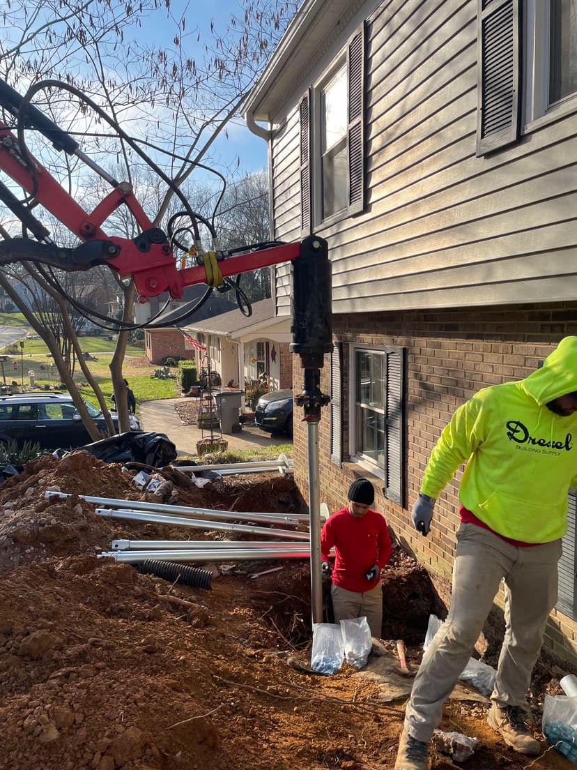 HydroHelp911 Crawl Space & Foundation Repair installing helical piers with a rotary drive head for foundation underpinning.
