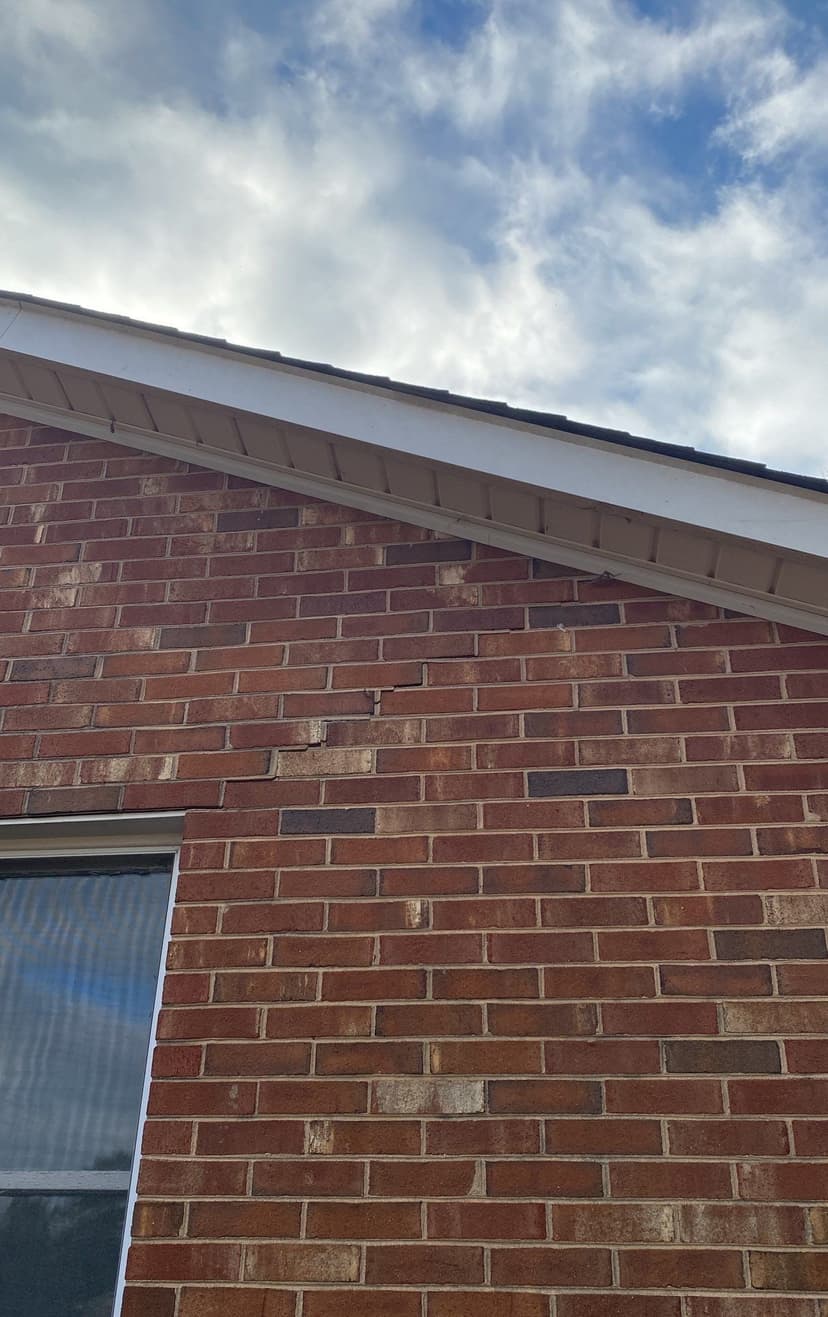 HydroHelp911 Crawl Space & Foundation Repair inspecting a stair step crack in exterior brick foundation.