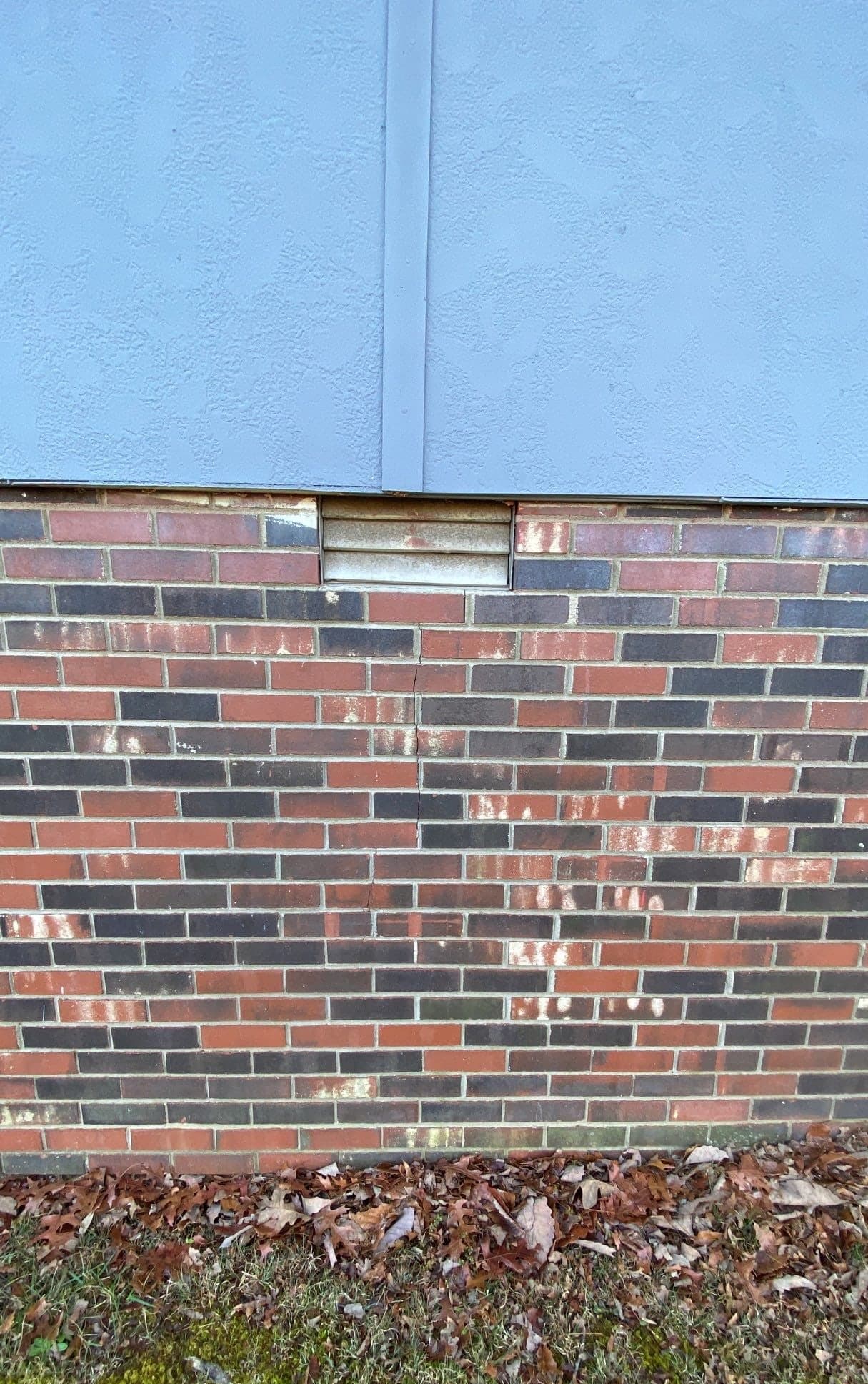 HydroHelp911 Crawl Space & Foundation Repair inspecting cracked bricks with diagonal cracks on a foundation wall.