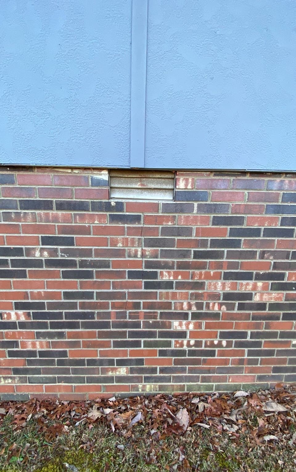 HydroHelp911 Crawl Space & Foundation Repair inspecting cracked bricks with diagonal cracks on a foundation wall.