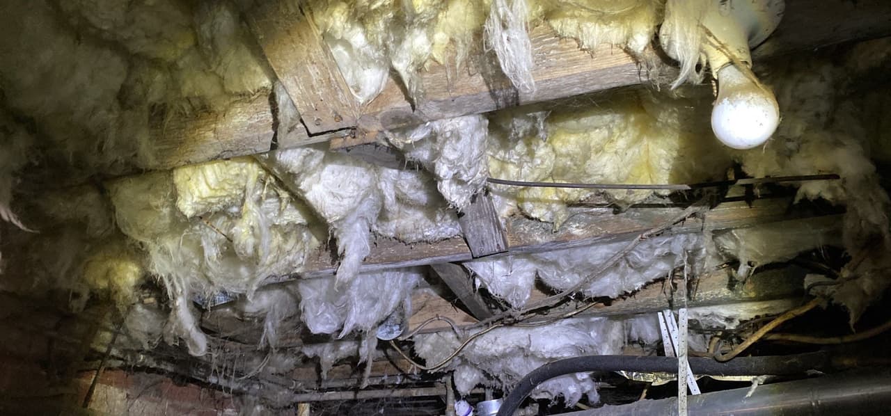 HydroHelp911 Crawl Space & Foundation Repair inspecting deteriorating insulation and wood rot in a damp crawl space.