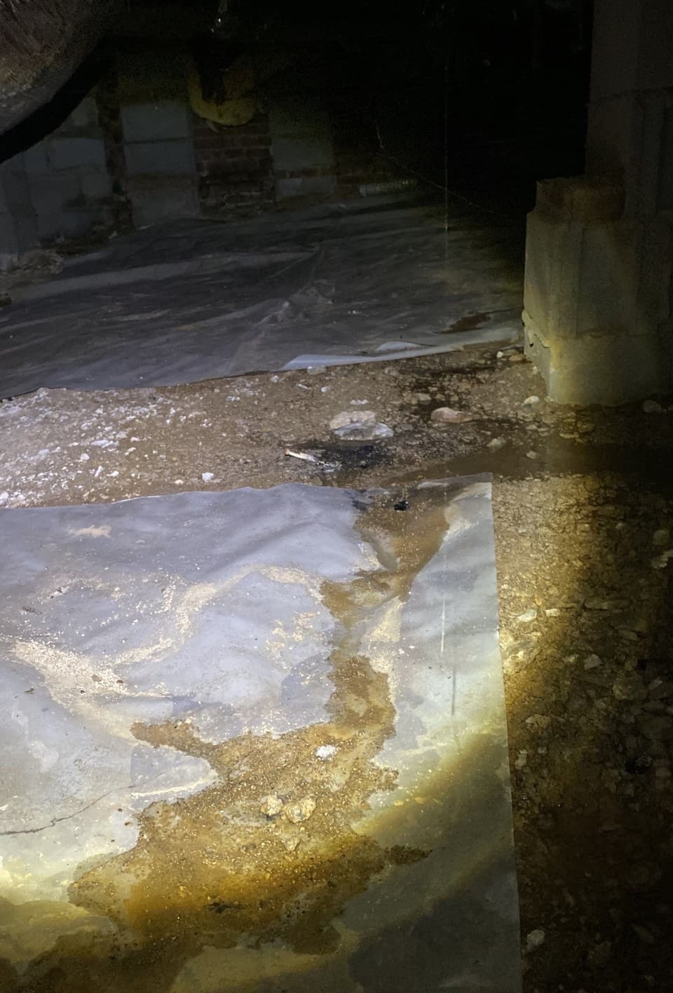 HydroHelp911 Crawl Space & Foundation Repair inspecting pooled water and moisture on existing ground cover in a crawl space.
