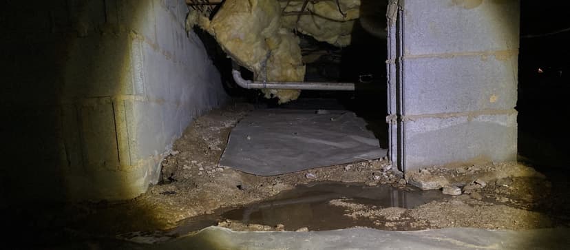 HydroHelp911 Crawl Space & Foundation Repair inspecting standing water in a damp crawl space with deteriorated insulation.