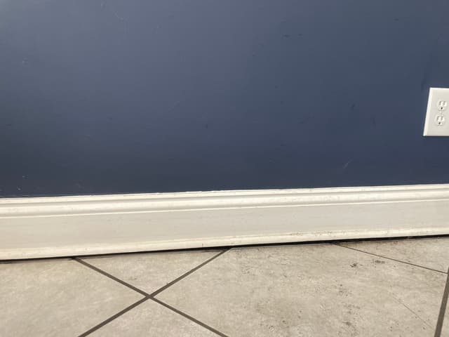 HydroHelp911 Crawl Space & Foundation Repair inspecting an uneven interior floor with a noticeable gap at the baseboard.