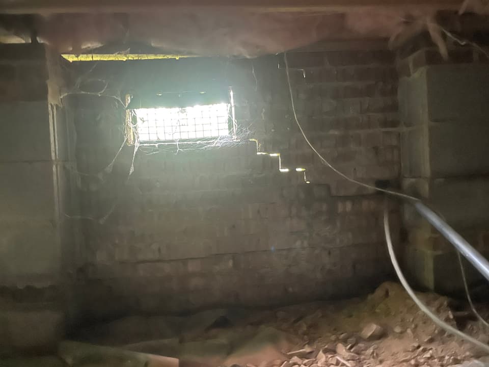 HydroHelp911 Crawl Space & Foundation Repair inspecting a stair step crack in a brick crawl space foundation.