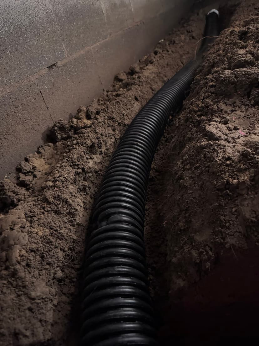 HydroHelp911 Crawl Space & Foundation Repair installing a crawl space drainage system with perforated pipe.