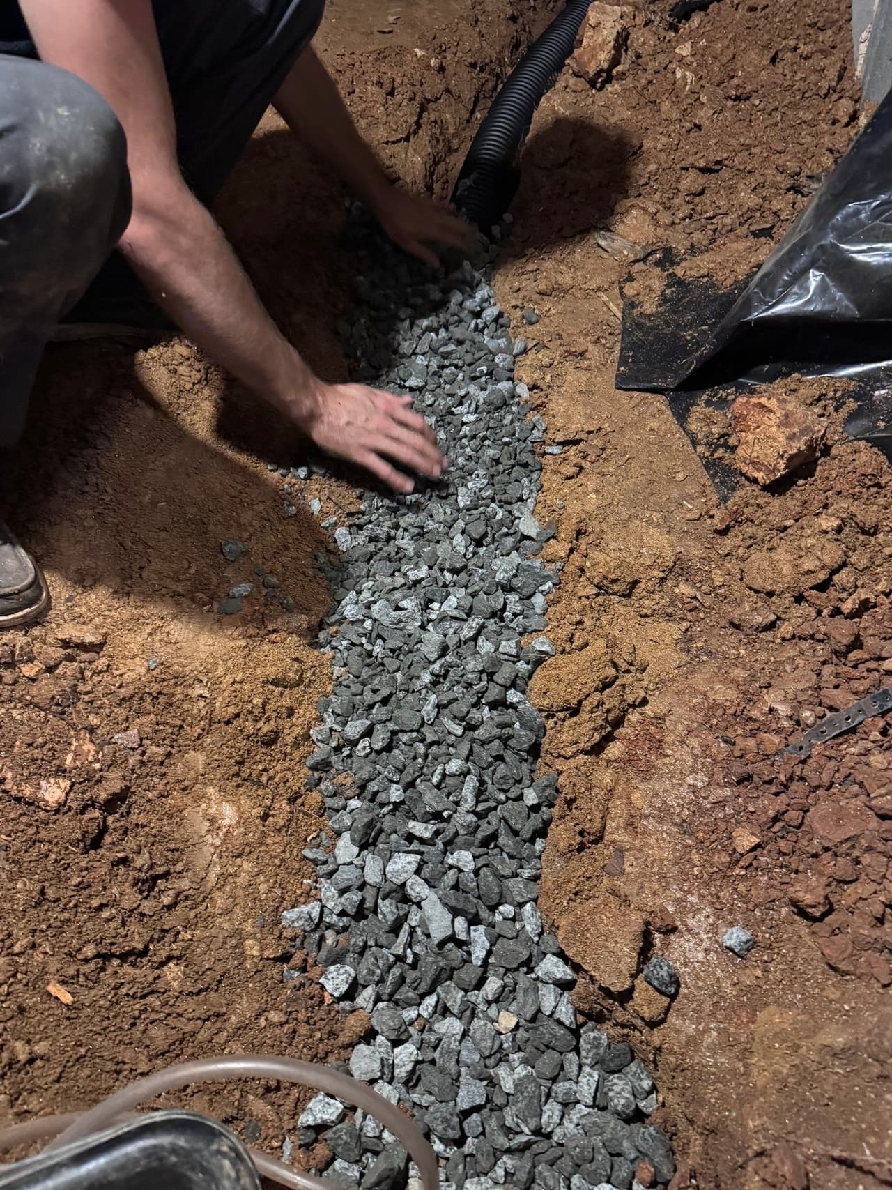 HydroHelp911 Crawl Space & Foundation Repair installing a crawl space drainage system with gravel and perforated pipe.