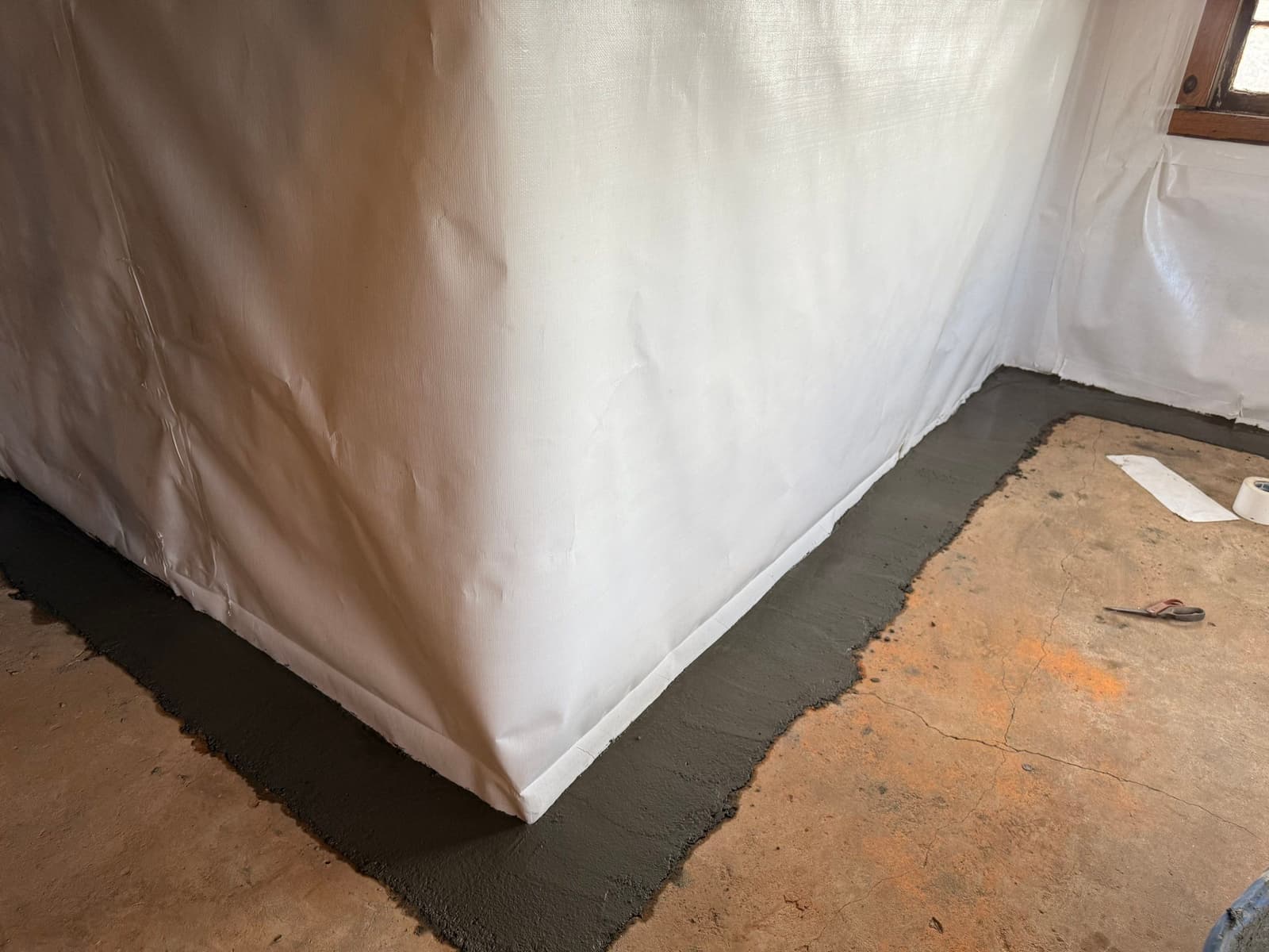 HydroHelp911 Crawl Space & Foundation Repair installing an interior drainage system with vapor barrier in a basement.